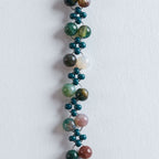 Farbe
Verschiedene Grüntöne, Naturbeige, Cremeweiß, feine marmorierte Steinstrukturen, goldene Akzente.