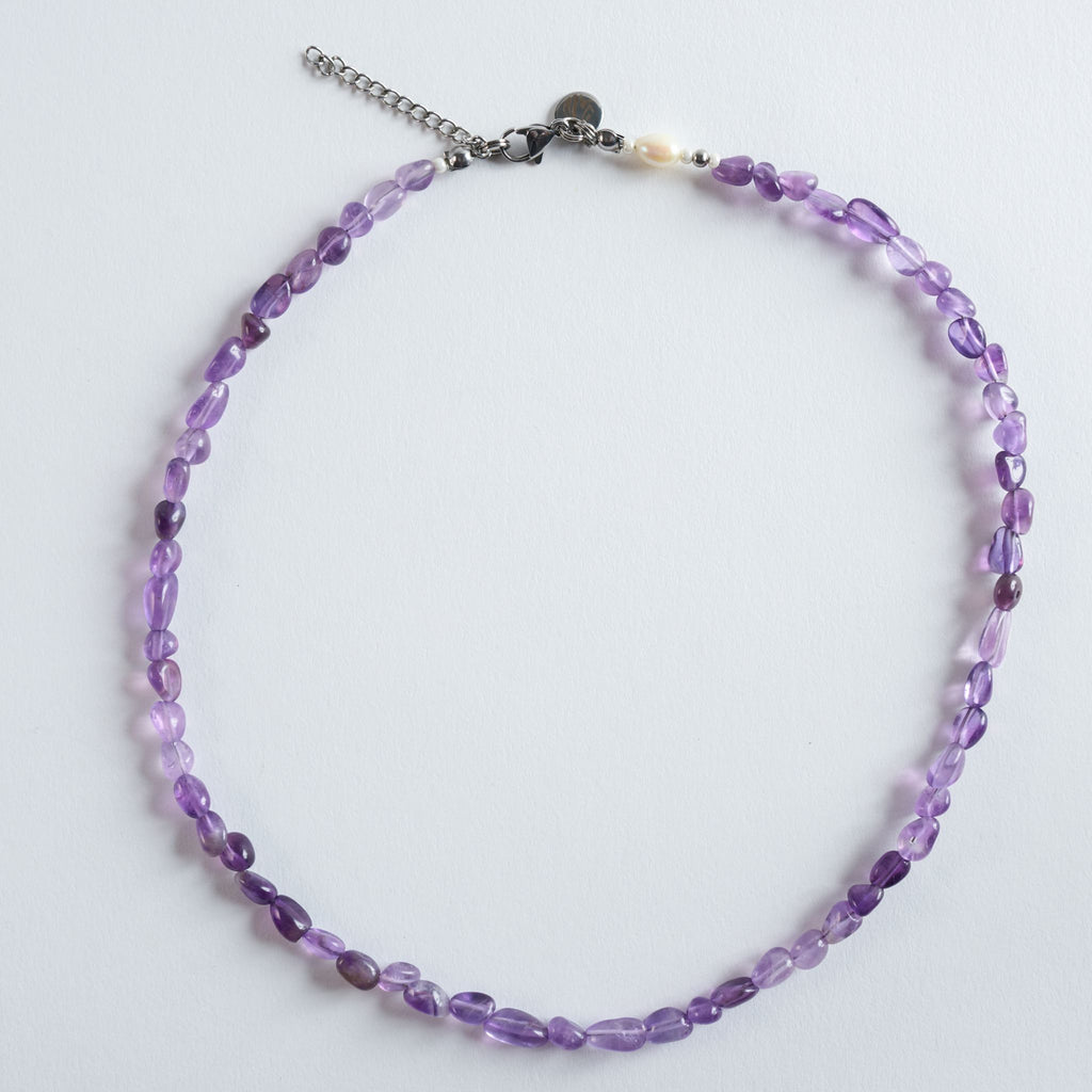 Geschliffene Amethyststeine in sanftem Violett bilden das Zentrum der Halskette "Violet Flow". Die natürliche Transparenz und die ungleichmäßige Struktur des Steins sorgen für einen authentischen, ruhigen Look.
