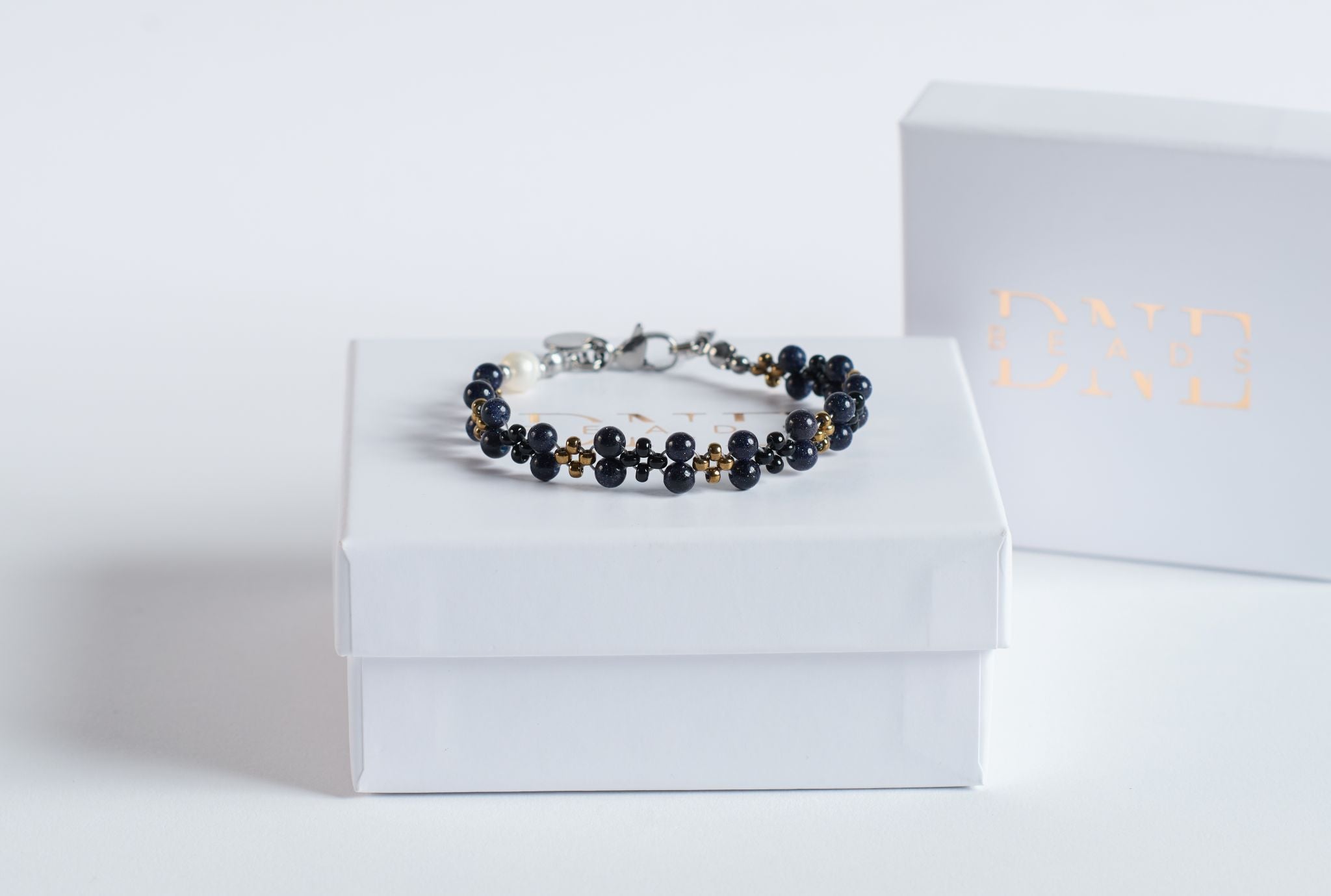 Das Twister–Armband Starlit&nbsp;Night verbindet tiefdunklen Blaufluss mit klitzekleinen goldenen Sprenkeln, die wie kleine Lichtpunkte im Stein schimmern.
In Kombination mit schwarzen und goldfarbenen Glasperlen entsteht durch die Twister-Struktur ein eleganter, fließender Verlauf, der an einen klaren Nachthimmel erinnert.