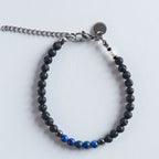 Das Armband Blue Lava verbindet die matte, natürliche Tiefe von Lavastein mit der kühlen Eleganz von Hämatit und der intensiven Farbwirkung echten Lapislazulis.

Die Kombination aus Schwarz, Silber und leuchtendem Blau erinnert an dunkle Felsformationen, die auf das tiefe Blau des Meeres treffen. Das Design wirkt kraftvoll, modern und klar. Ein stilvoller Akzent für jeden Tag.