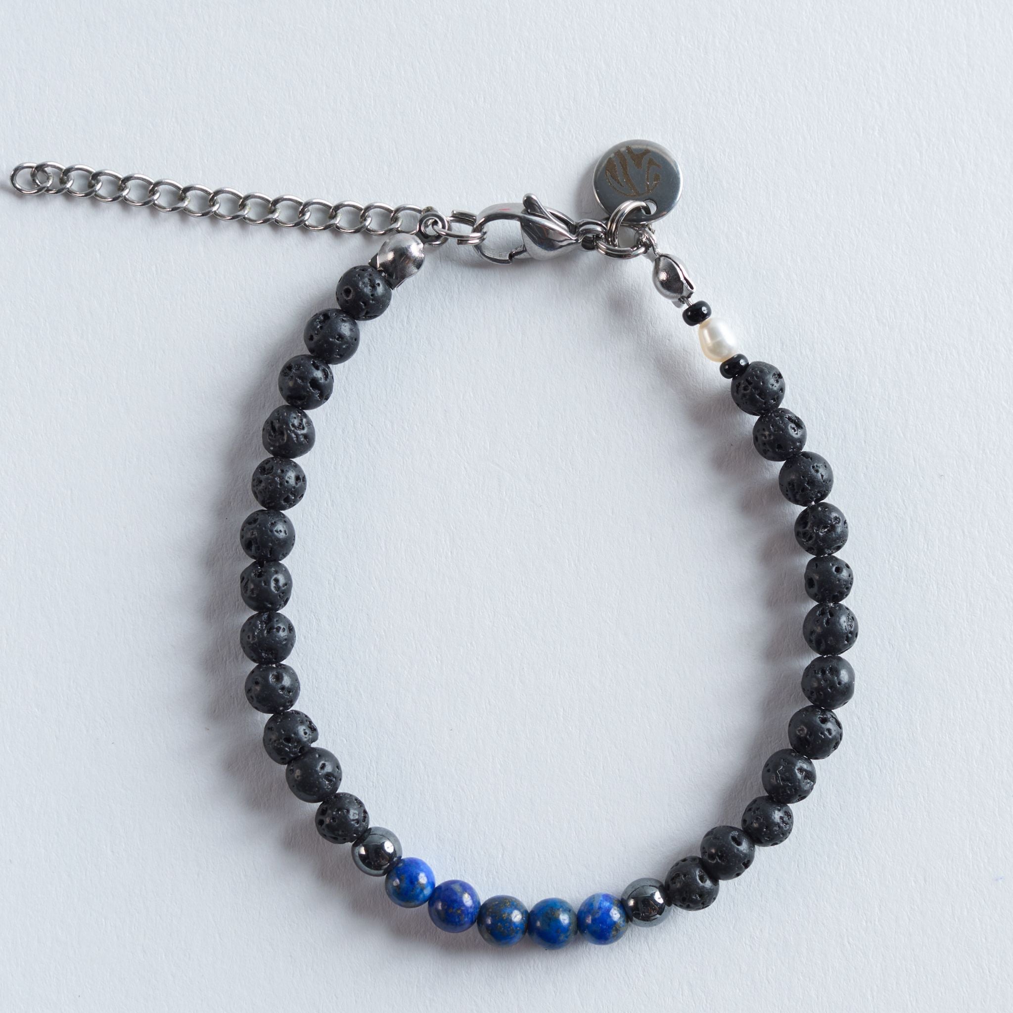 Das Armband Blue Lava verbindet die matte, natürliche Tiefe von Lavastein mit der kühlen Eleganz von Hämatit und der intensiven Farbwirkung echten Lapislazulis.

Die Kombination aus Schwarz, Silber und leuchtendem Blau erinnert an dunkle Felsformationen, die auf das tiefe Blau des Meeres treffen. Das Design wirkt kraftvoll, modern und klar. Ein stilvoller Akzent für jeden Tag.