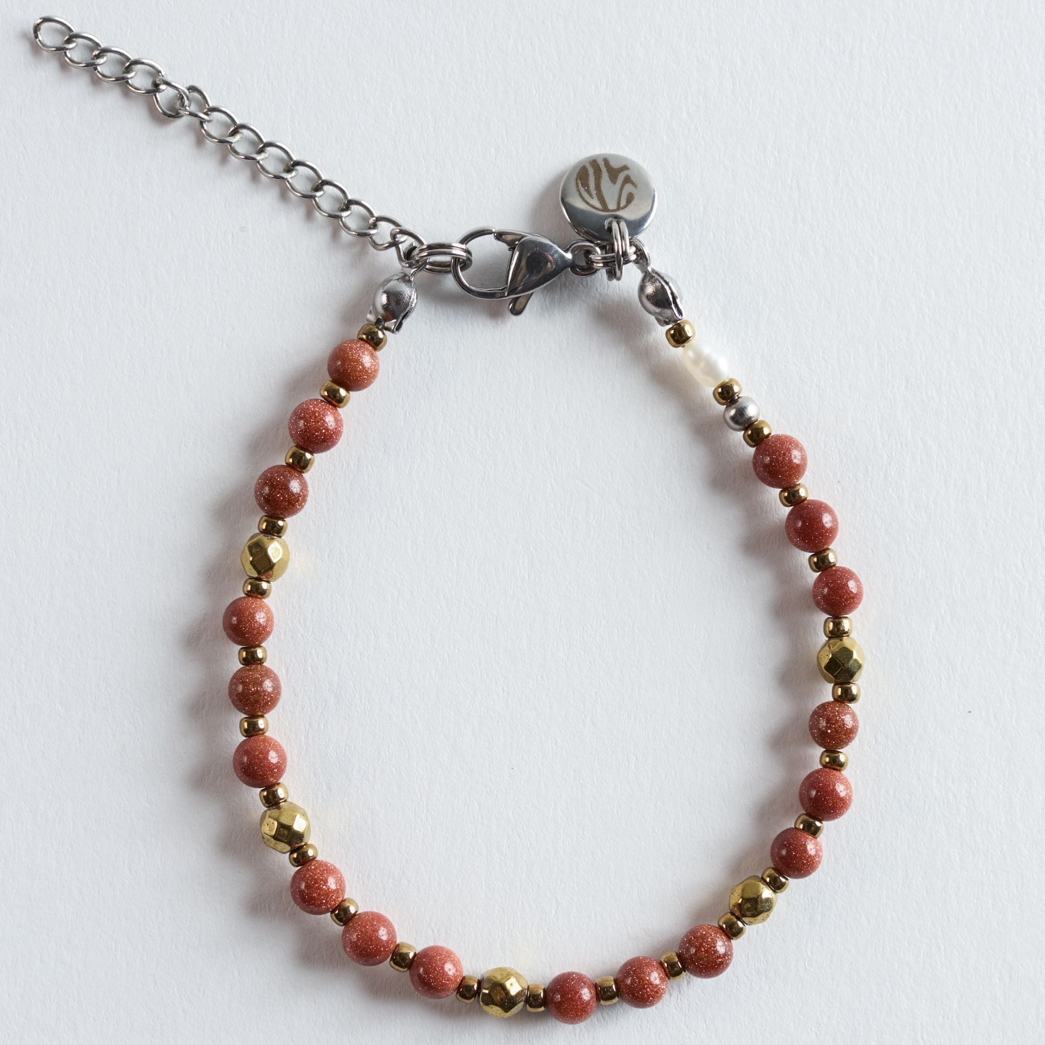 Das Armband Ember verbindet warm schimmernden Goldfluss mit feinen Hämatit-Details zu einem klaren, eleganten Design. Der synthetische Goldfluss zeigt seinen charakteristischen, goldenen Schimmer, der je nach Lichteinfall weich aufleuchtet. Hämatit bringt mit seinem modernen, metallischen Glanz einen präzisen Kontrast ein und verleiht dem Armband eine leichte grafische Note.