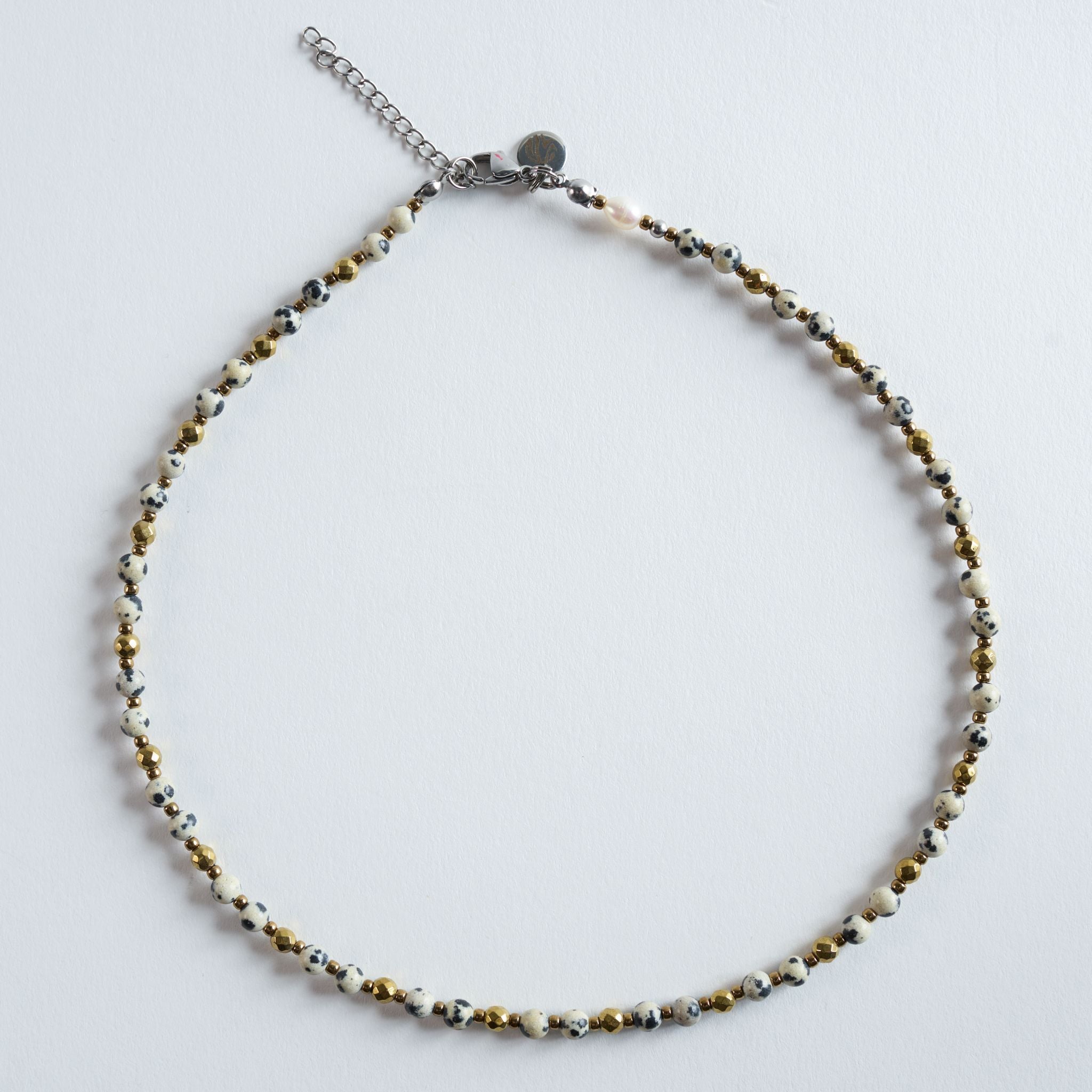 Die Kette „Dalmatiner“ kombiniert gesprenkelten Dalmatiner Jaspis mit goldfarbenem Hämatit. Die charakteristischen Punkte des Natursteins verleihen dem Design eine moderne, leichte Struktur, während die goldenen Akzente einen warmen, eleganten Kontrast setzen.