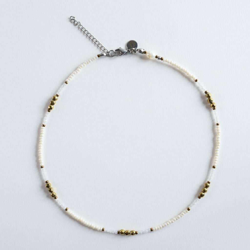 Die Halskette „Ivory“ kombiniert feine, helle Perlen mit goldenen Akzenten zu einem klaren, eleganten Design. Die zarten Weiß- und Cremetöne wirken leicht und modern, während die goldfarbenen Hämatitdetails dem Schmuckstück eine hochwertige, warme Note verleihen. Ein minimalistisches, stilvolles Modell, das sich vielseitig stylen lässt – ob einzeln oder im Layering.