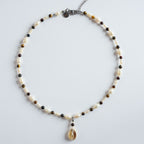 Die Halskette „Golden Coast“ kombiniert warm schimmerndes Tigerauge mit natürlichen Süßwasserperlen und einem Muschelanhänger.