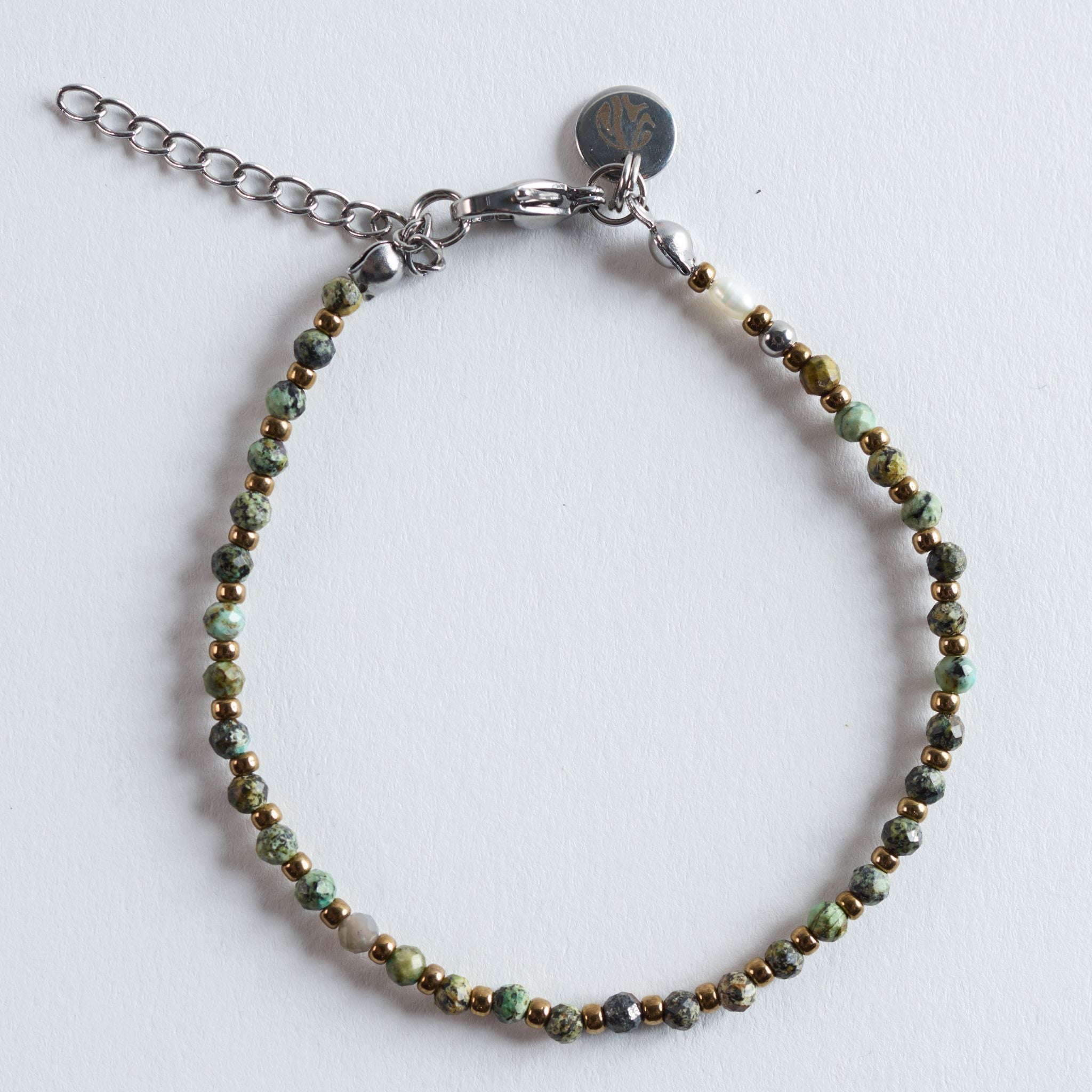 Das Armband Golden Forest übersetzt die warmen Lichtmomente eines Waldes in ein feines Schmuckstück. Grüne Natursteine werden von goldfarbenen Glasperlen eingerahmt und erinnern an Sonnenstrahlen, die zwischen Blättern und Moos aufblitzen.
