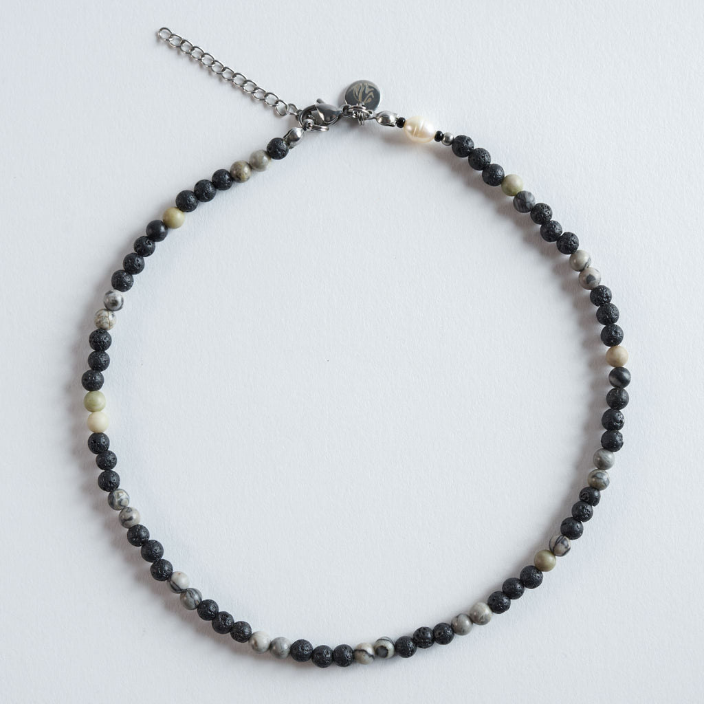 Die Kette „Grey Lava“ vereint die markante Textur von Lavastein mit sanft gemusterten Picture-Jasper-Perlen (Safari Jasper). Die Kombination aus tiefem Schwarz und natürlichen Grau-Beige-Schattierungen erzeugt einen ruhigen, minimalistischen Look. Ein dezentes, neutrales Design, das sich mit jedem Stil kombinieren lässt.