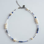 Die Perlenkette „Blue Chaos“ verbindet echte Süßwasserperlen mit tiefblauem Lapislazuli und klaren Glasperlen zu einem markanten, modernen Design.