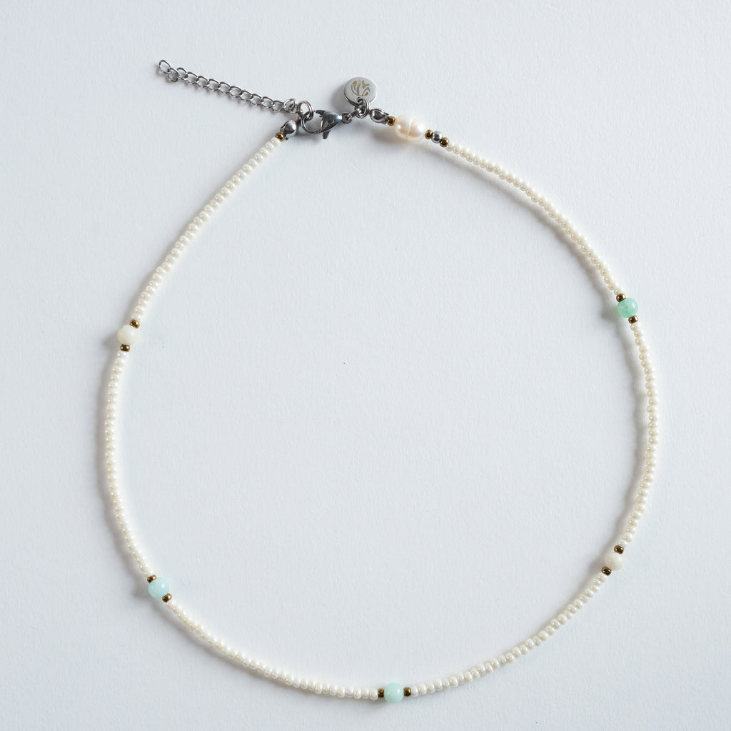Die Halskette „Ice“ kombiniert zart schimmernde Süßwasserperlen mit einem klaren, mintgrünen Amazonit und feinen goldfarbenen Details. 