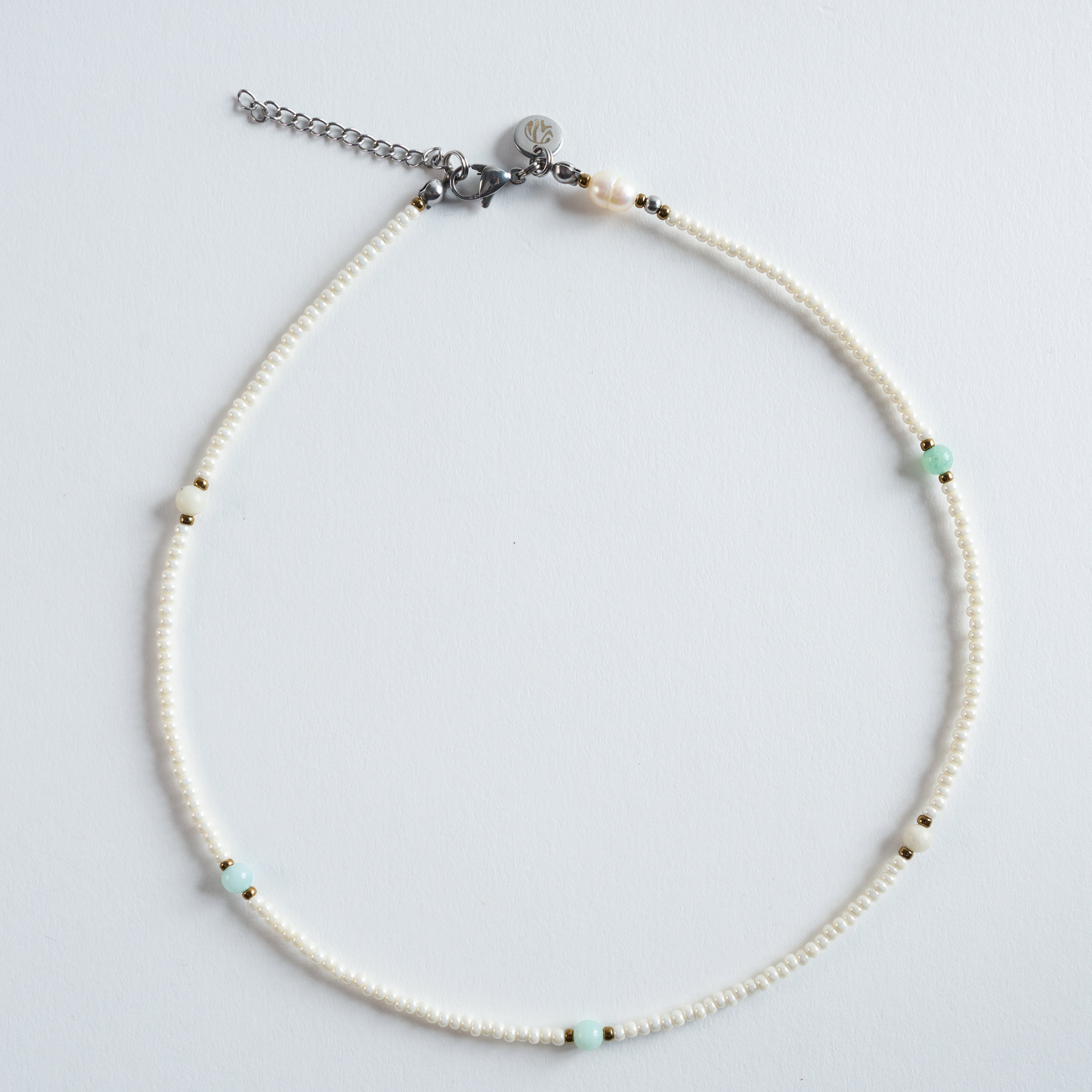 Die Halskette „Ice“ kombiniert zart schimmernde Süßwasserperlen mit einem klaren, mintgrünen Amazonit und feinen goldfarbenen Details. 