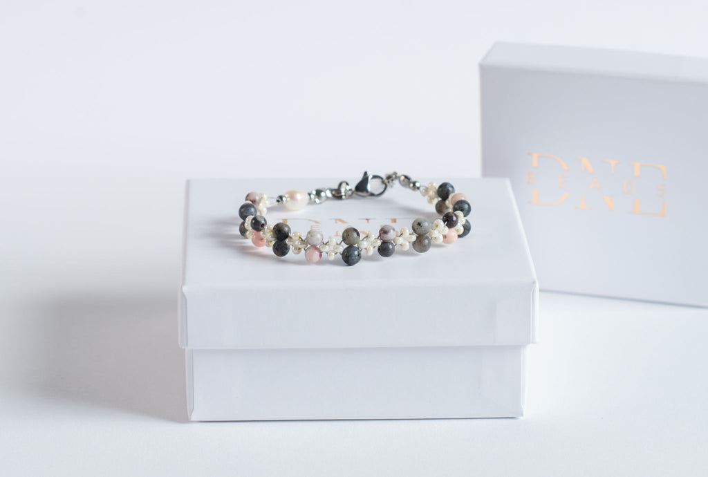 Das Twister-Armband Misty Rose vereint grauen Labradorit mit sanft roséfarbenem Jaspis und feinen weißen Blütenperlen zu einem ruhigen, eleganten Design. Die gedrehte Struktur lässt die Steinperlen wie eine zarte Farbspur ums Handgelenk fließen und verleiht dem Armband einen leicht nebligen, roséfarbenen Schimmer.