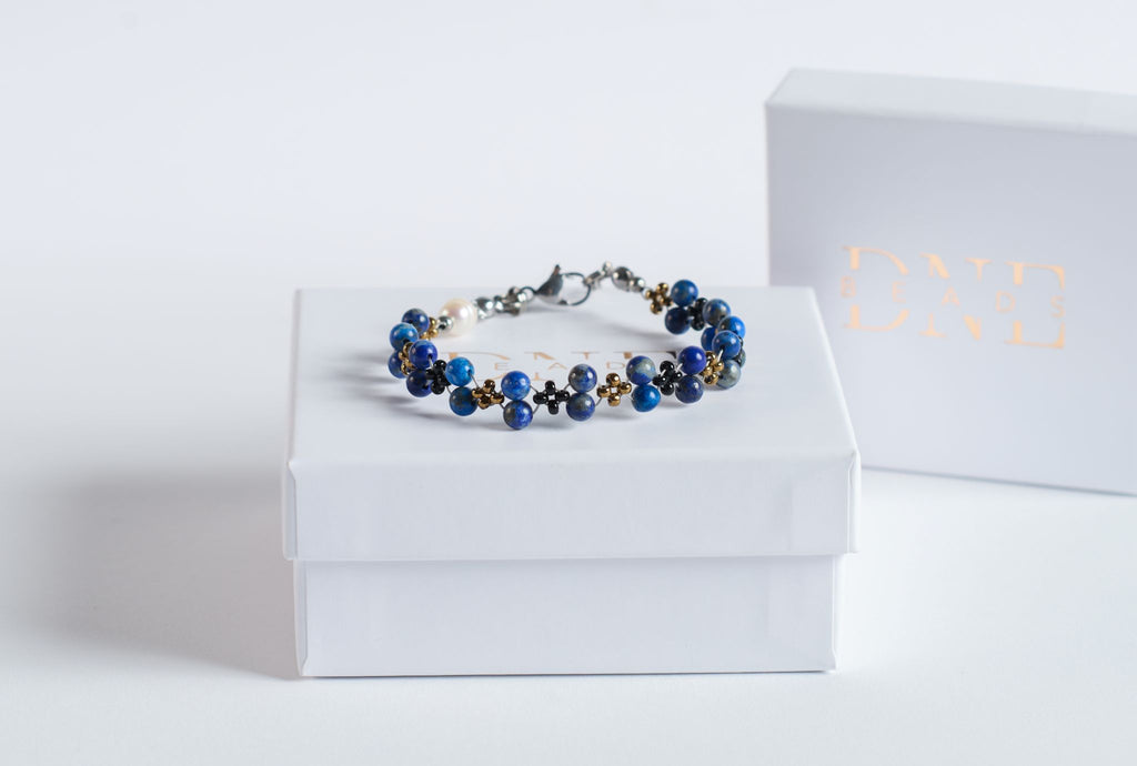 Das Twister-Armband Deep Sea verbindet die charakteristische Tiefe des Lapis Lazuli mit einer dynamischen Twister-Struktur, die an die Bewegung des Meeres erinnert.

Die intensiven Blautöne des Natursteins changieren je nach Lichteinfall zwischen Königsblau, Marine und kleinen goldenen Einschlüssen, die typisch für echten Lapis sind. Schwarze und goldfarbene Akzentperlen rahmen die Steine ein und verstärken die maritime Farbwelt.