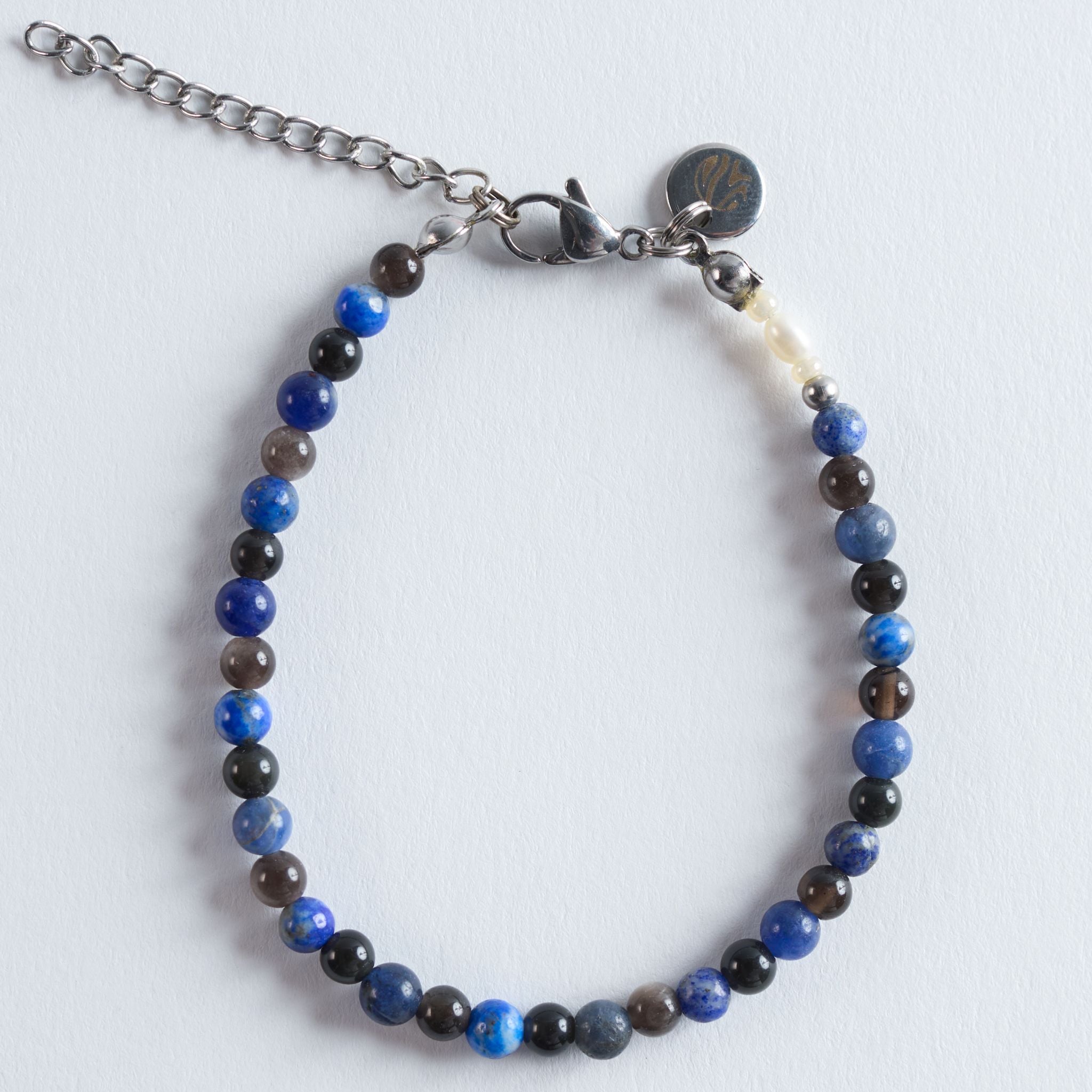 Das Armband Blue Orbit kombiniert intensives Königsblau von Lapislazuli mit den weich strukturierten Blautönen von Sodalit und der Tiefe von schwarzem Obsidian. Das Design wirkt modern, klar und ruhig. Ein Armband mit einer starken, eleganten Ausstrahlung.