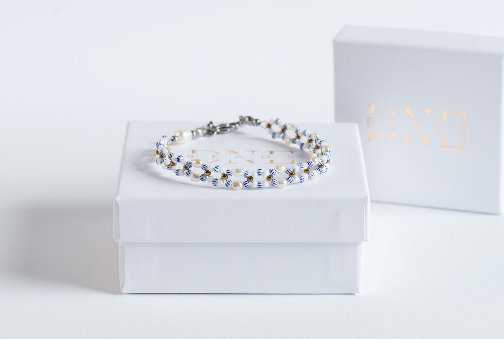Das Twister-Armband Mama Mia verbindet helle Süßwasserperlen mit blau-weiß gestreiften Glasperlen und goldfarbenen Highlights. Die Twister-Struktur schafft ein lebendiges, maritimes Muster, das an Sommer, Leichtigkeit und Meeresfarben erinnert. Die Kombination aus Weiß, Blau und Gold wirkt frisch und modern.