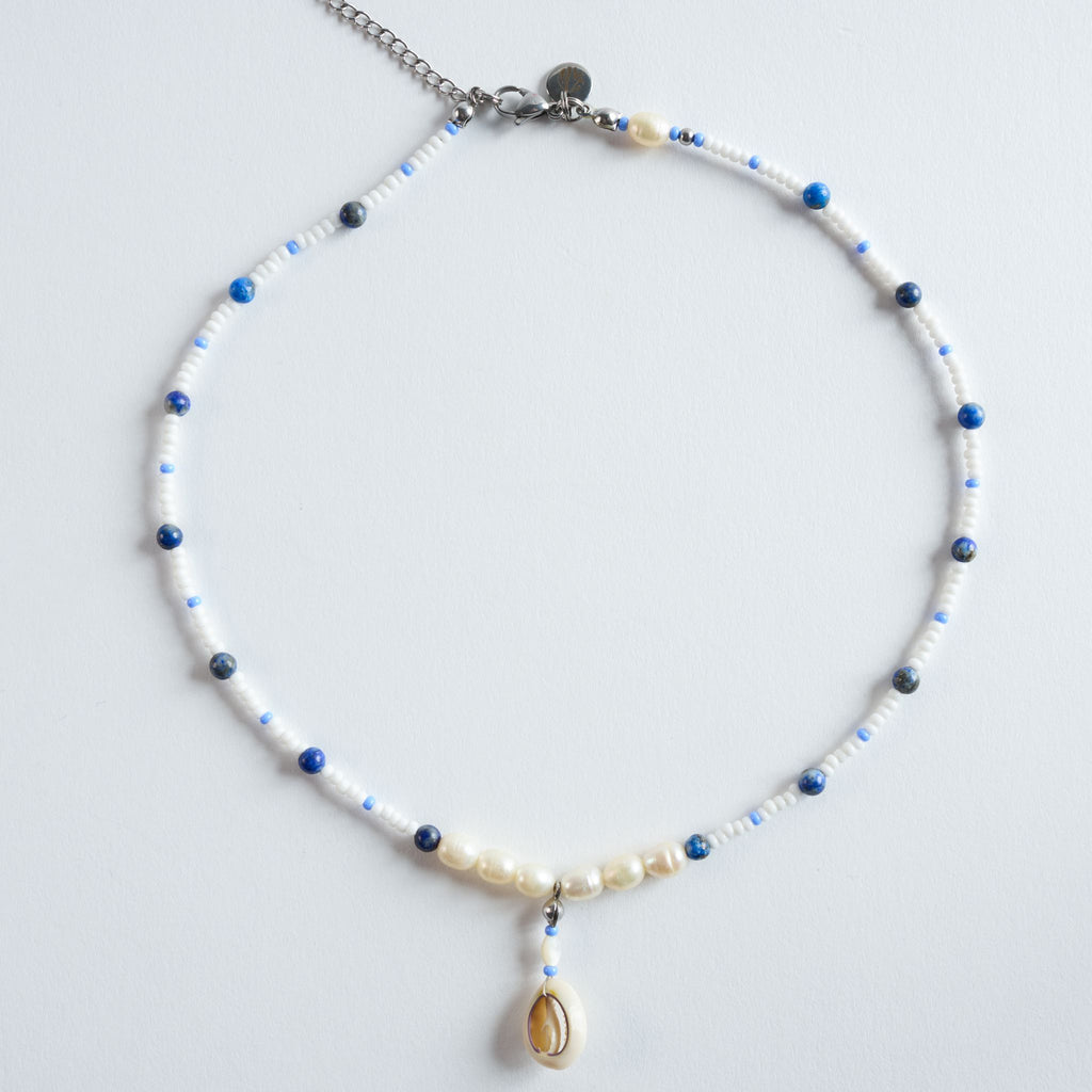 Die Halskette „Ocean Breeze“ verbindet tiefblauen Lapis Lazuli mit zarten Süßwasserperlen und hellen Glasperlen zu einem klaren, maritimen Design.