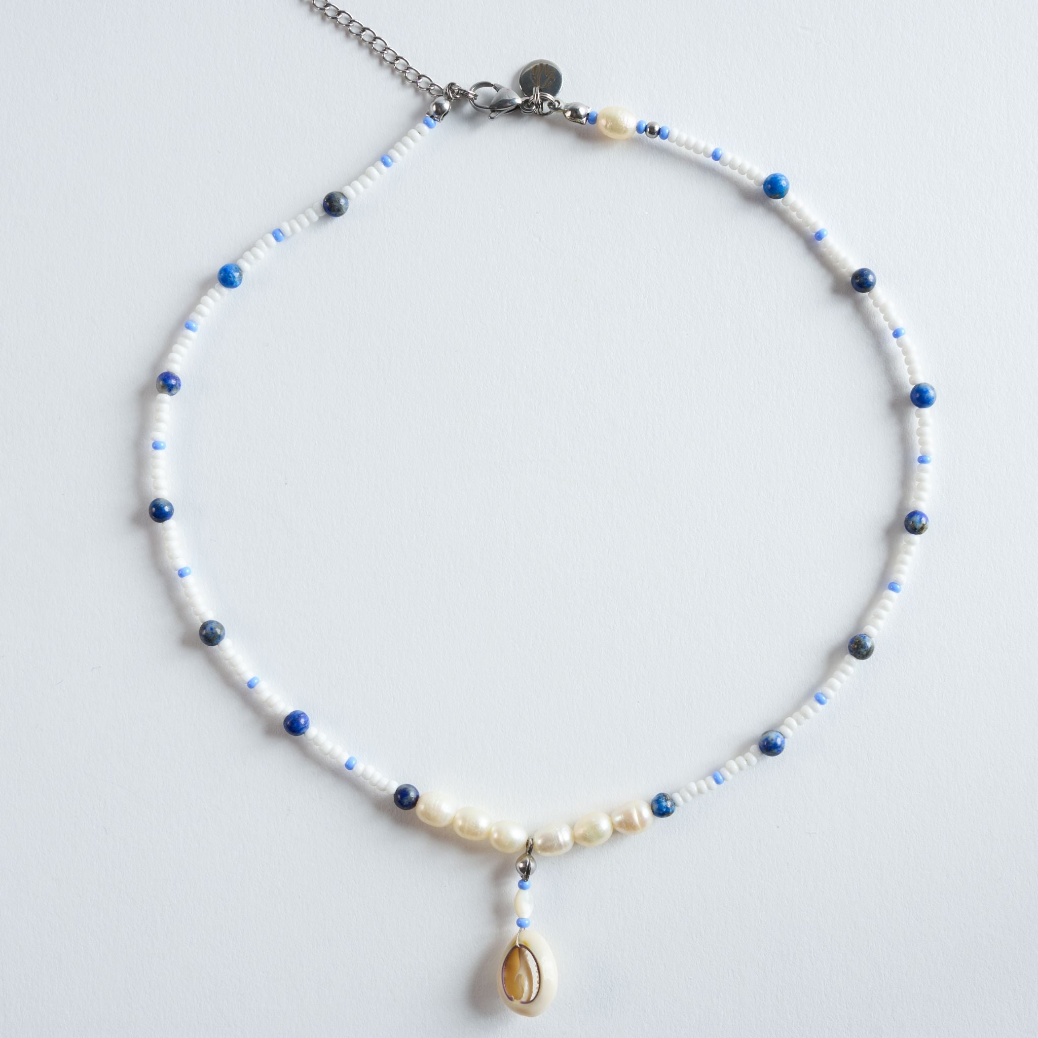 Die Halskette „Ocean Breeze“ verbindet tiefblauen Lapis Lazuli mit zarten Süßwasserperlen und hellen Glasperlen zu einem klaren, maritimen Design.