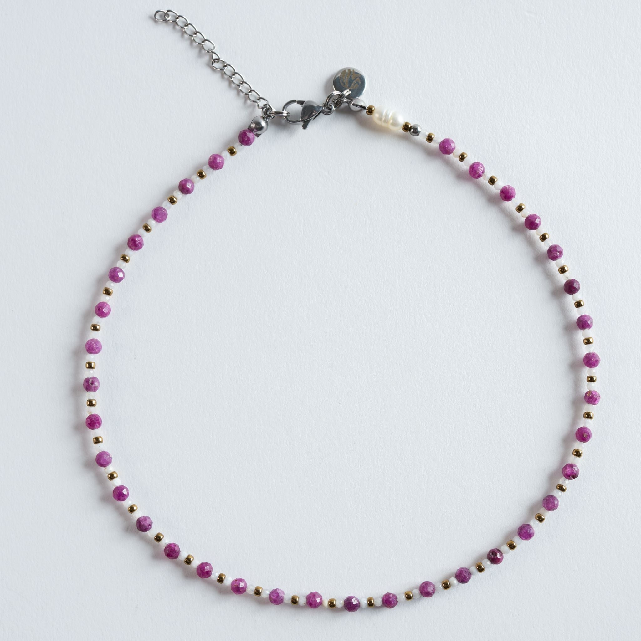 Die Halskette „Rubin – Essence“ kombiniert facettierte Rubinperlen mit hellen Zwischenperlen und goldfarbenem Hämatit. Die feinen Facetten erzeugen kleine Lichtreflexe, die den warmen Pinkton des Rubins elegant hervorheben. Ein modernes, hochwertiges Design mit klarer, femininer Ausstrahlung.