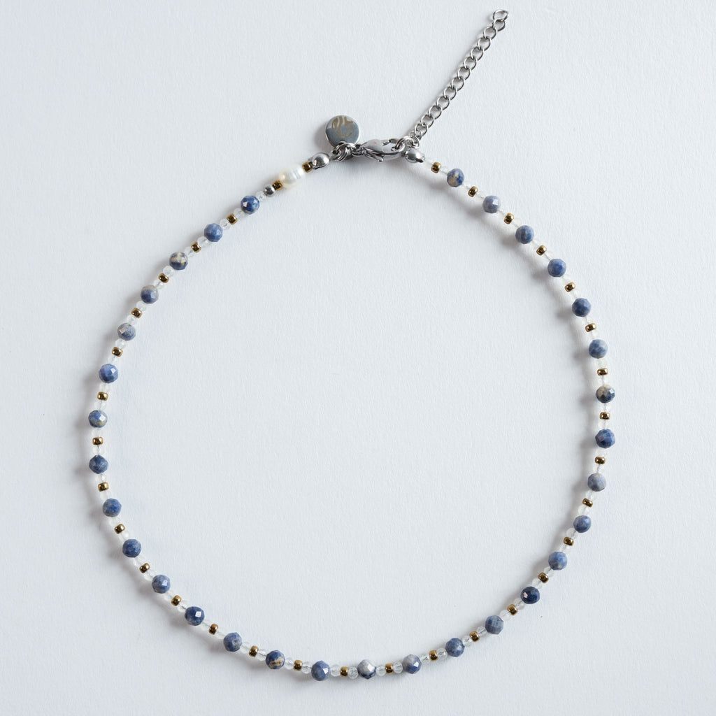 Die Kette „Saphir – Essence“ vereint facettierte Saphirperlen in sanft marmorierten Blautönen mit hellen Zwischenperlen und goldfarbenem Hämatit. Das Design wirkt klar, ruhig und elegant – ein zeitloses Schmuckstück mit feiner Struktur.