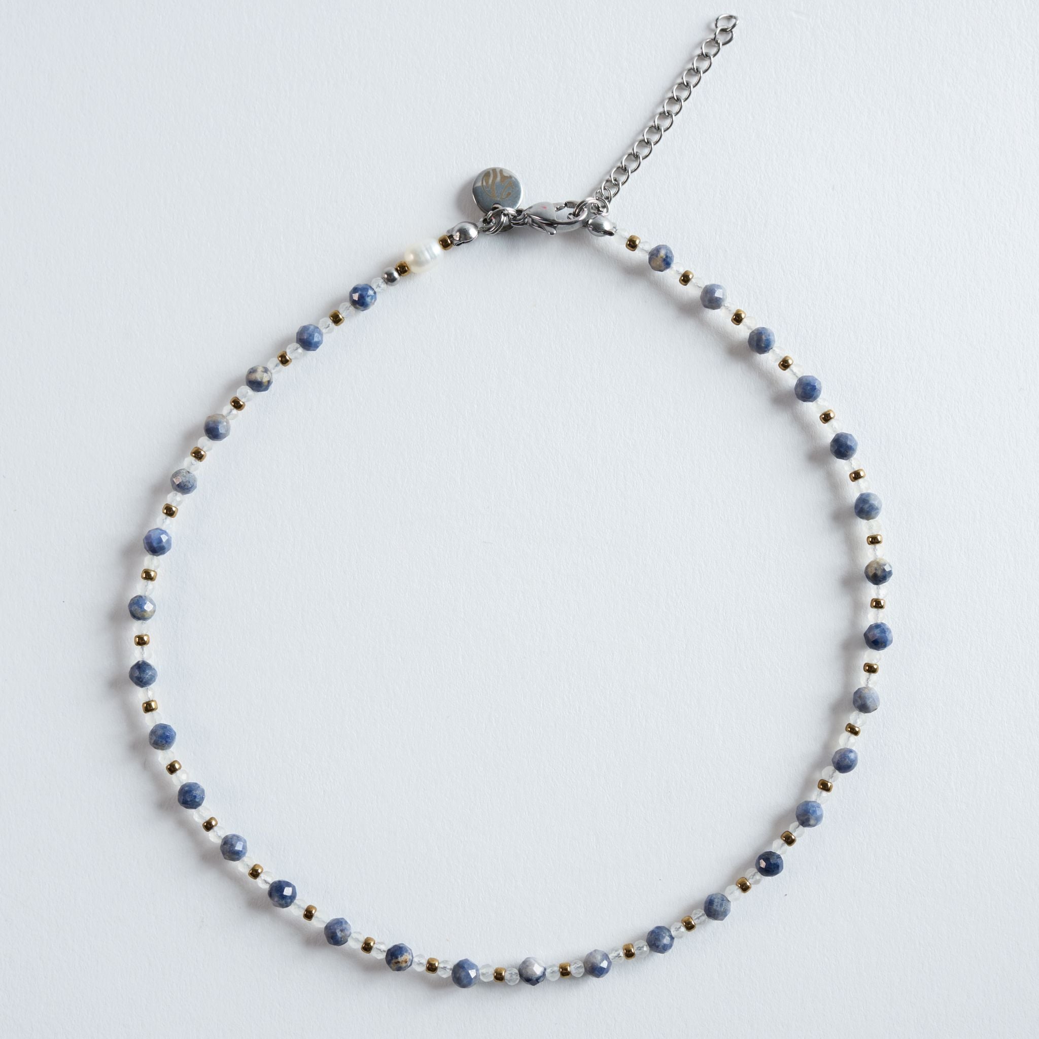 Die Kette „Saphir – Essence“ vereint facettierte Saphirperlen in sanft marmorierten Blautönen mit hellen Zwischenperlen und goldfarbenem Hämatit. Das Design wirkt klar, ruhig und elegant – ein zeitloses Schmuckstück mit feiner Struktur.