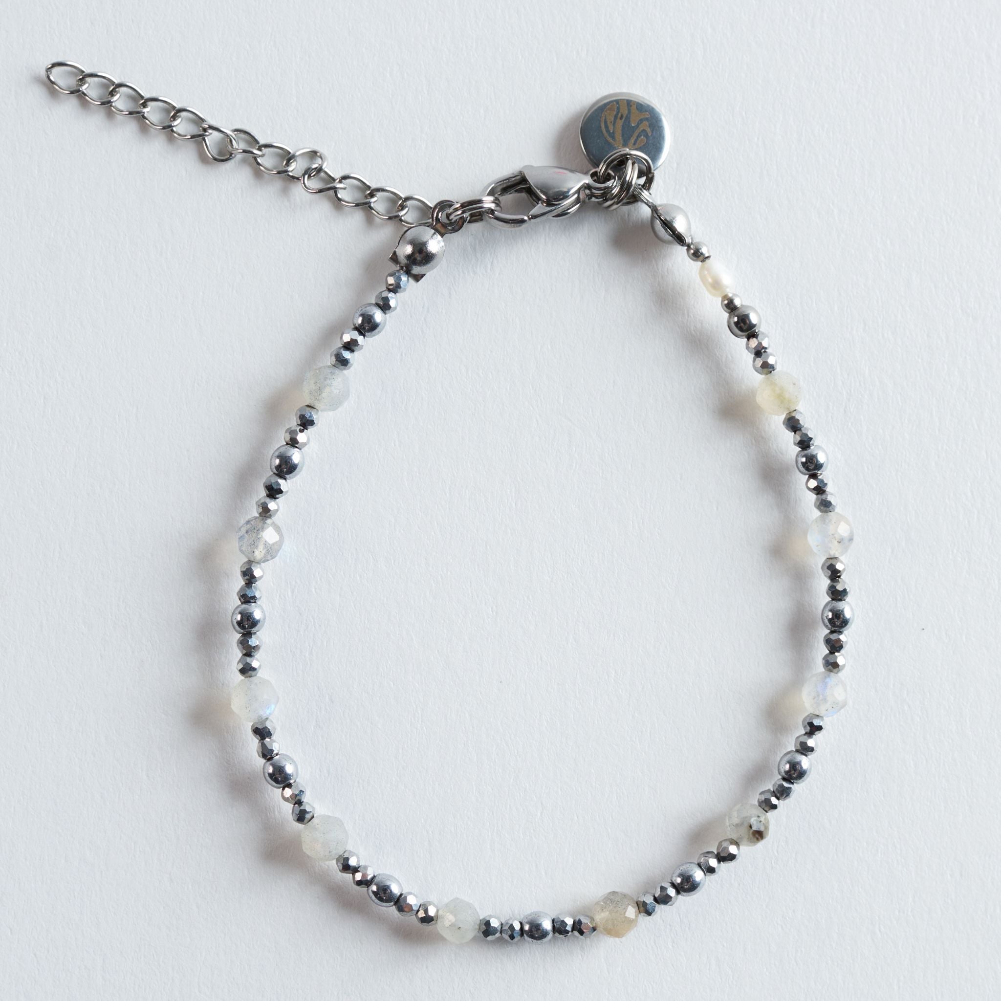 Das Armband Lunar Essence vereint sanft schimmernden Labradorit mit klar glänzendem Hämatit zu einem kühlen, lichtreflektierenden Design. Labradorit zeigt seinen charakteristischen, zarten Schimmer, der je nach Lichteinfall feine Blau- und Grautöne andeutet. Hämatit setzt dazu präzise, silberne Akzente und verleiht dem Armband eine moderne, klare Struktur.