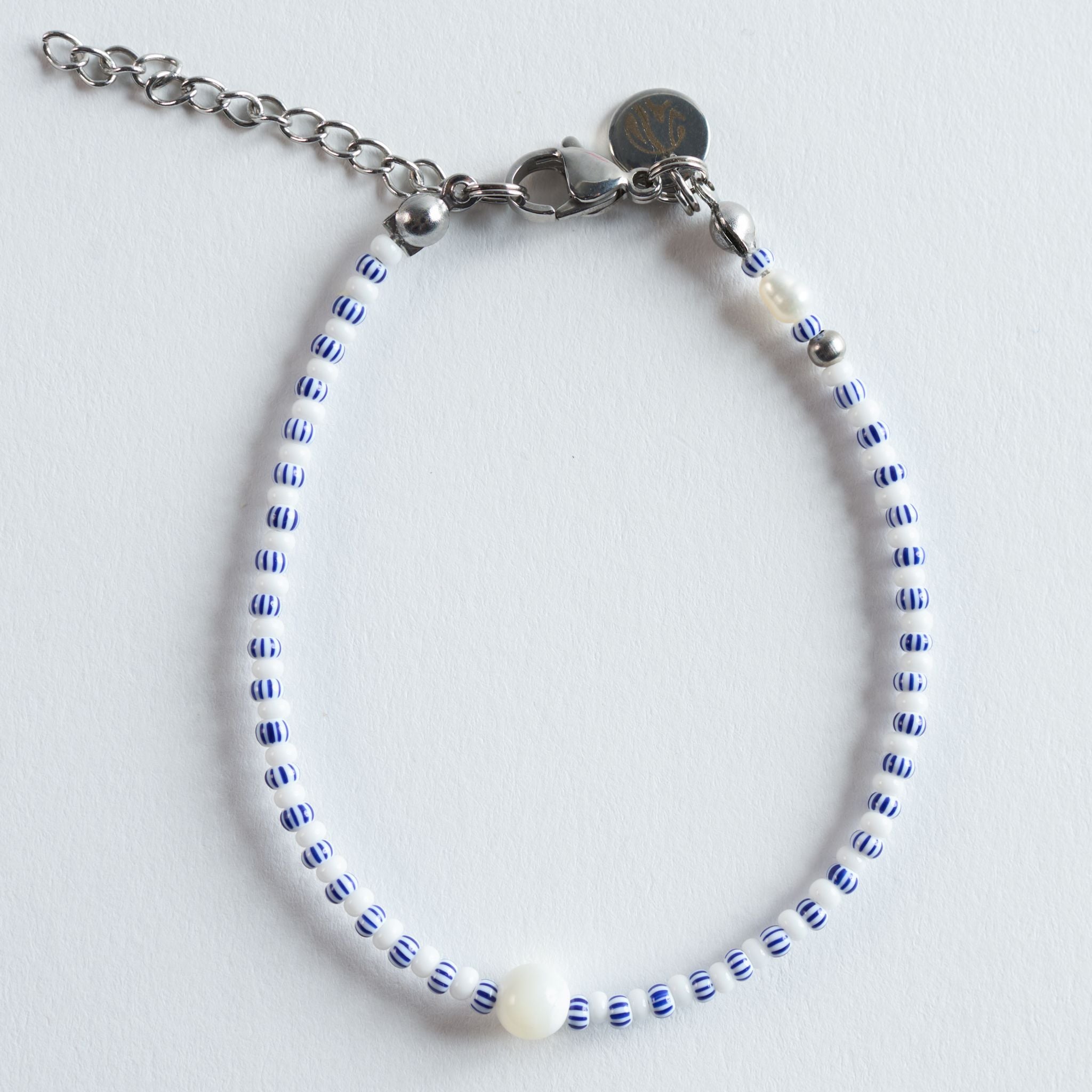 Das Armband Strip kombiniert feine blau-weiß gestreifte Glasperlen mit einem dezenten Perlmutt-Akzent und klaren Edelstahl-Details. Das leichte, maritime Design erinnert an Sommertage am Meer: helle Farben, frische Linien und ein minimalistischer Rhythmus, der dezent ins Auge.