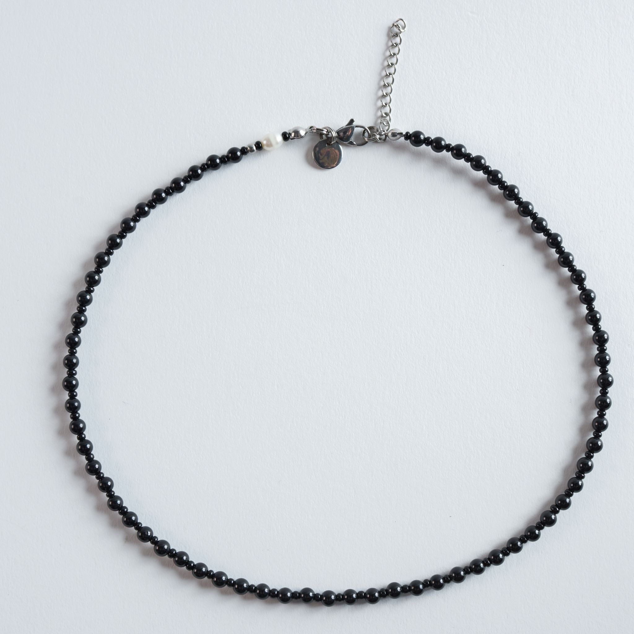 Die Halskette „Raven“ verbindet tiefschwarzen Turmalin mit einer klaren, organischen Linienführung. Die glatten, dunklen Steine wirken natürlich und zugleich elegant, während ihre feinen Reflexe dem Design eine ruhige Tiefe verleihen.

Durch die leicht unregelmäßigen Formen entsteht eine authentische, erdige Struktur, die den charaktervollen Look des Turmalins betont.