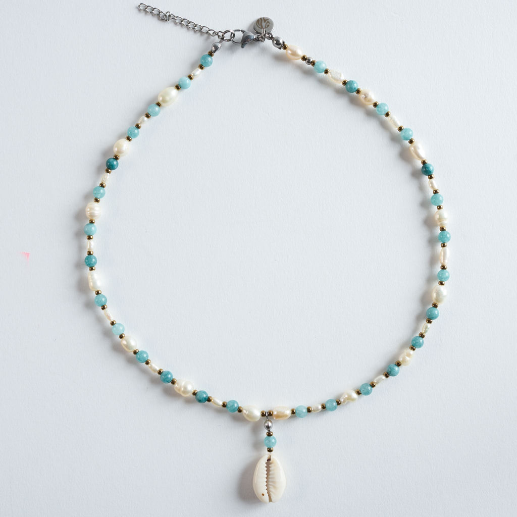 Die Halskette „Wave“ vereint feinen Aquamarin mit eleganten Süßwasserperlen und einem natürlichen Muschelanhänger.